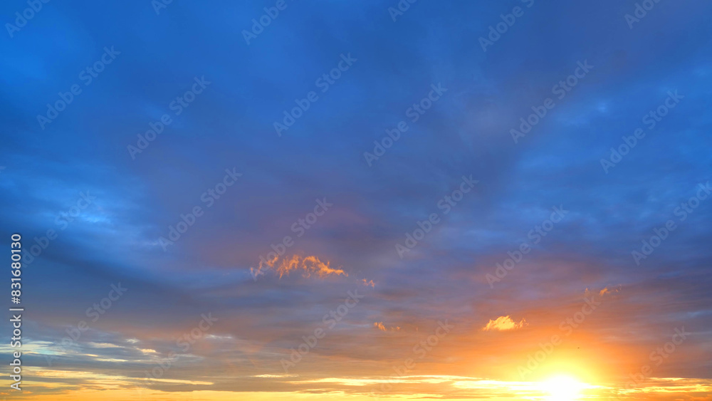 Fototapeta premium A magnificent sunrise with the sun casting a golden glow over the horizon. The sky transitions from deep blue at the top to warm shades of orange and yellow near the horizon. Sunrise sky background. 