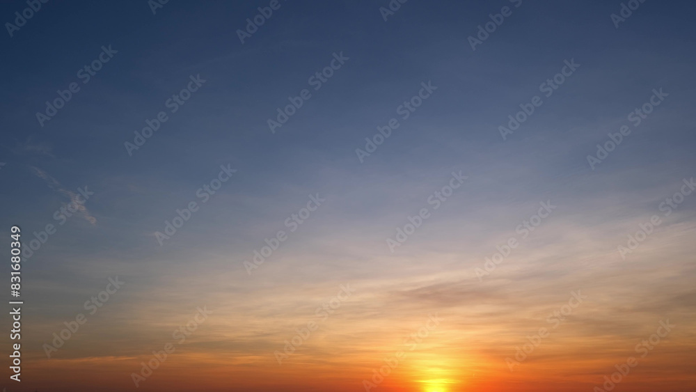 A serene sunrise with the sun just above the horizon, casting warm orange and yellow tones that gradually blend into the cool blue sky, creating a peaceful gradient effect. Sunrise sky background.
