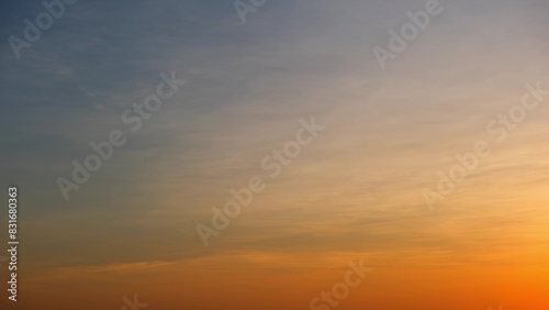 A soft gradient from orange at the horizon to a muted blue at the top, with delicate, wispy clouds enhancing the serene and tranquil atmosphere of the sunset. Cloud background.  © Punyawee