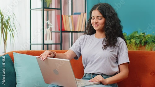 Indian woman sitting on couch closing laptop after finishing work in living room. Young Arabian girl freelancer works online remote job at home sofa. E-learning, browsing internet on notebook computer