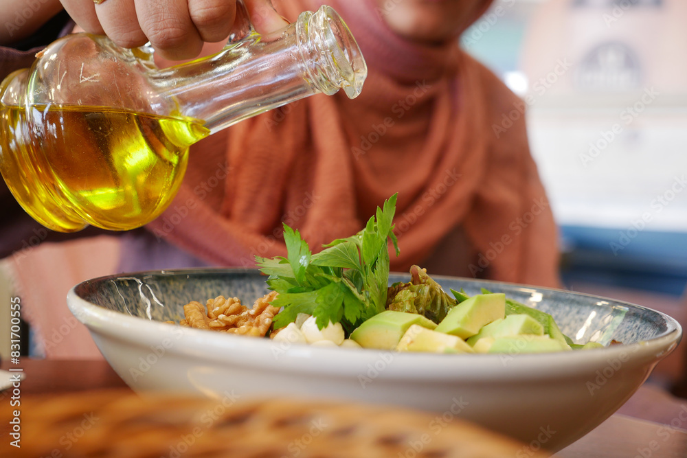 Obraz premium Healthy Salad Prep with Olive Oil in a Cozy Restaurant. Enjoy a fresh and wholesome meal