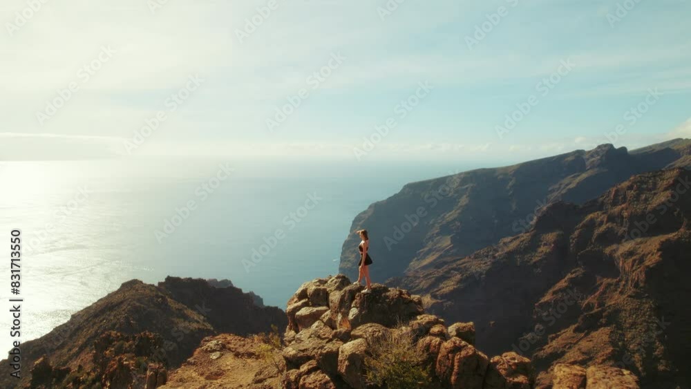Solo traveler observes the Atlantic from a high vantage point on Tenerife rugged cliffs. Peacefulness of being above the coastal landscape. Solo traveler observes the Atlantic from a high vantage point on Tenerife rugged cliffs. Peacefulness of being above the coastal landscape.