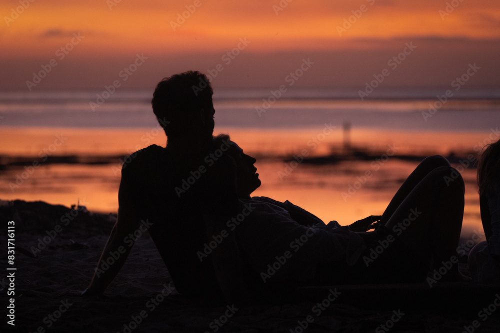 Fototapeta premium Couple watching the sunset on the beach.