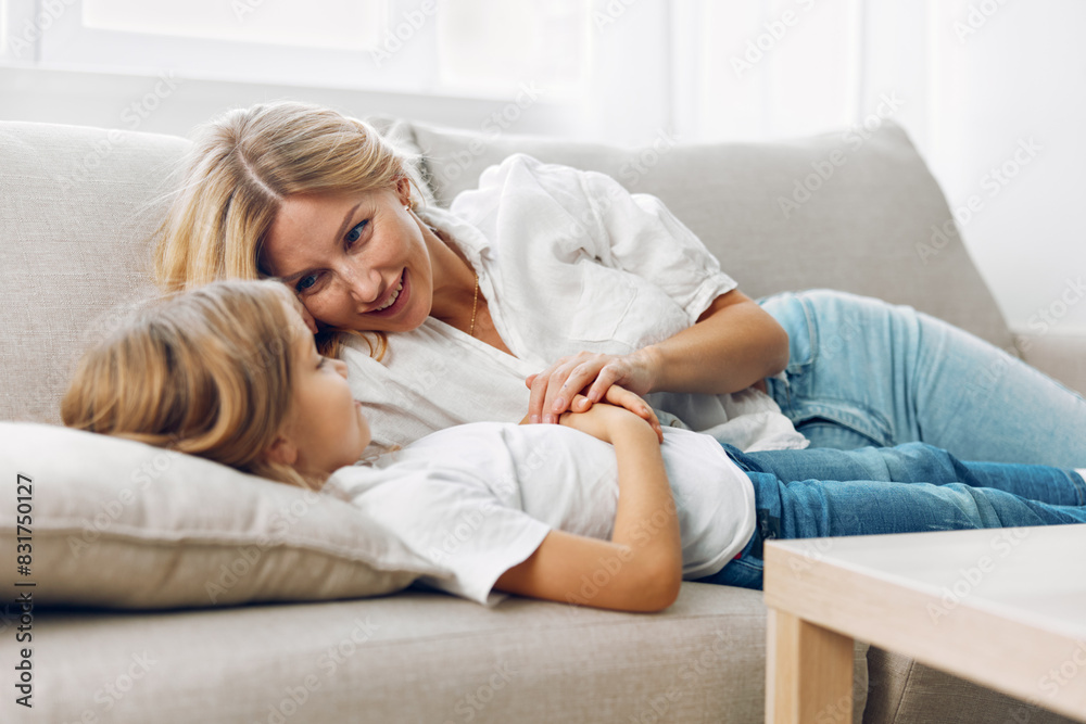 Mother and daughter enjoying a cozy movie night on the couch in a warmly lit living room Mother and daughter enjoying a cozy movie night on the couch in a warmly lit living room