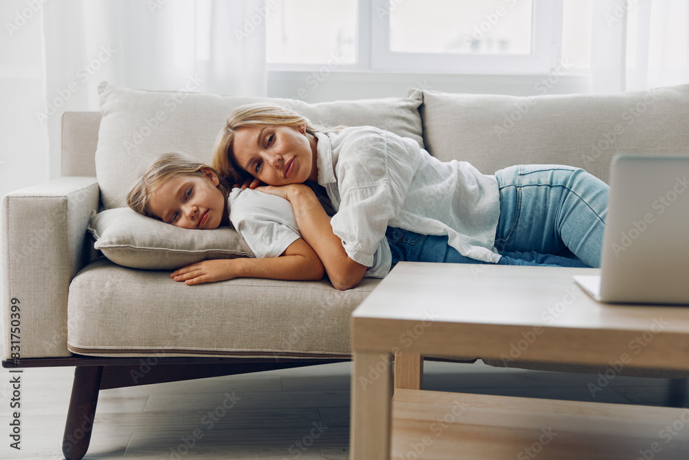 Mother and daughter peacefully napping on a cozy couch with a laptop resting nearby in a serene living room Mother and daughter peacefully napping on a cozy couch with a laptop resting nearby in a serene living room