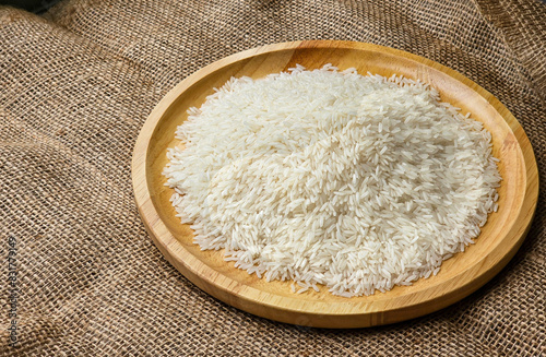 Side view, rice grains on a wooden plate. sackcloth background