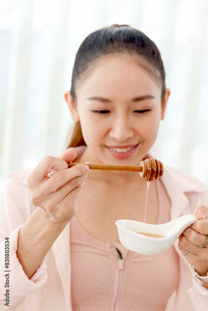 Beautiful happy smiling Asian woman looking at good honey source of sweetness for healthy food and beverage drink. Sporty girl making healthy diet from sweet honey to lose weight, get slim and healthy Beautiful happy smiling Asian woman looking at good honey source of sweetness for healthy food and beverage drink. Sporty girl making healthy diet from sweet honey to lose weight, get slim and healthy