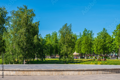 Open stone stage in the park on the background of summer  public park as pedestal for your creativity.