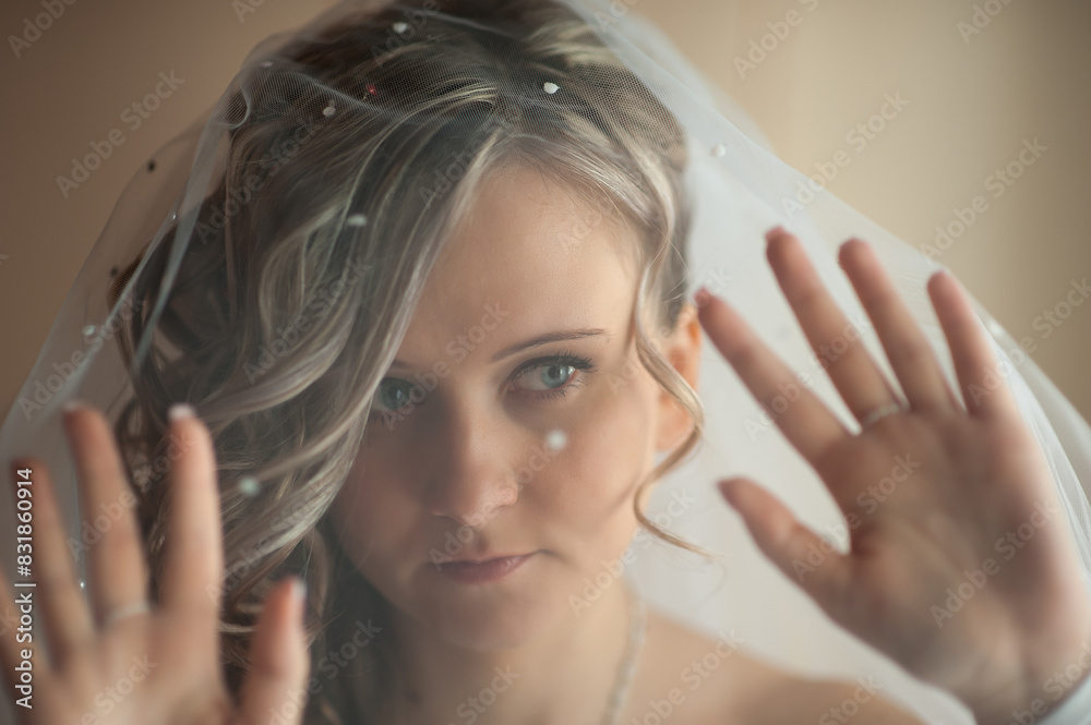 Fototapeta premium Morning of the bride in a white dress and elegant hairstyle. Young attractive, happy girl posing at home. Happiness, purpose and dream wedding.