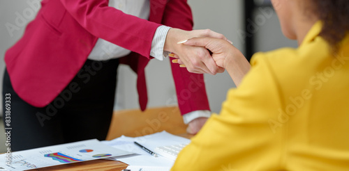 Two businesswomen hold hands on a table while finishing a work briefing. An agreement or partnership to invest in a financial business online marketing startup business idea.