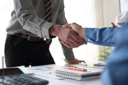 Businessmen shake hands to end the meeting. Successful negotiations and handshakes Group of business people congratulating each other inside the office.