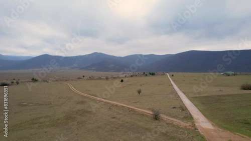 A beautiful landscape drone video of an empty field with a road in Croatia region Lika in Europe (ID: 831896351)