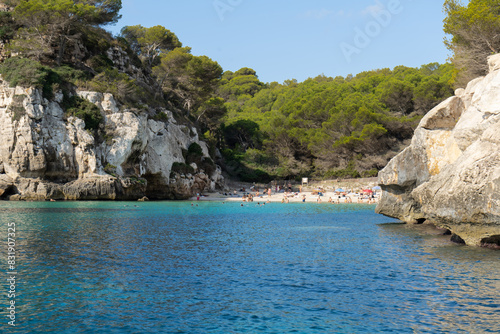 Cala de Macarelleta on the island of Menorca with people bathing on vacation surrounded by vegetation. Balearic Islands Tourism photo
