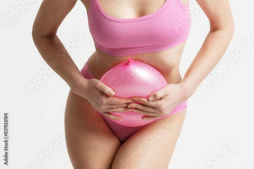 Fotografia Young woman holding balloon as a sign of an stomach inflation, bloating and mens