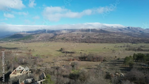 Beautiful aerial shot of Croatian landscape with wind turbines generating renewable energy in the background and an empty road, in the region of Lika in Croatia, Europe (ID: 831928180)