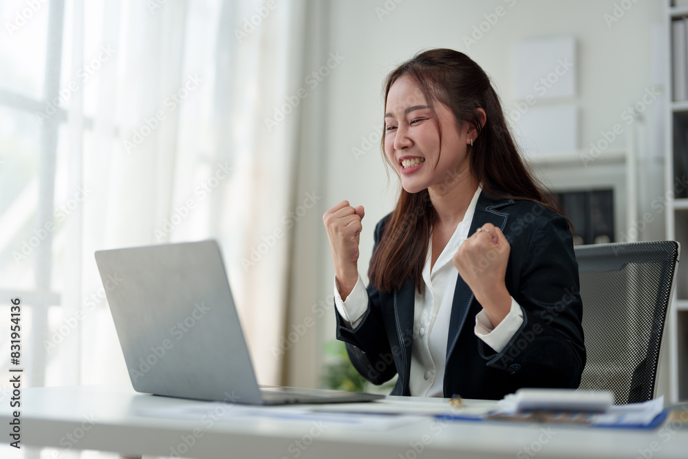 Surprised and happy businesswoman shows joyful expression after viewing news results, business approval results and financial approval results on laptop at office. Startup business growth concept. Surprised and happy businesswoman shows joyful expression after viewing news results, business approval results and financial approval results on laptop at office. Startup business growth concept.