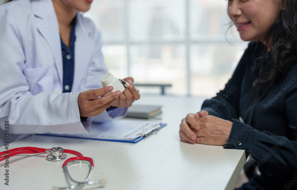 Fototapeta premium Doctor, female pharmacist points to a medicine bottle, gives advice, recommends how to take medicine to an elderly female patient. Explaining prescriptions, medical system concepts and health care.