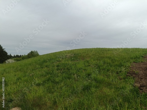 Salduve hill during cloudy day. Small hill. Grass is growing on hill. Staircase leading to the top. Cloudy day with white and gray clouds in sky. Nature. Salduves piliakalnis.