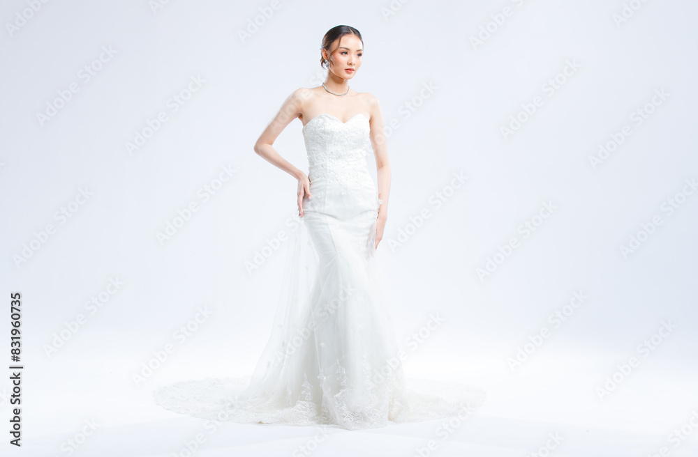 Asian young beautiful female portrait attractive model of bride wearing fashion wedding dress, luxury delight make-up, hairstyle, standing looking camera isolated white background studio indoor photo Asian young beautiful female portrait attractive model of bride wearing fashion wedding dress, luxury delight make-up, hairstyle, standing looking camera isolated white background studio indoor photo