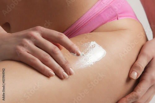 Woman applying body lotion to moisturize her skin after shower, beauty skin care concept	 photo
