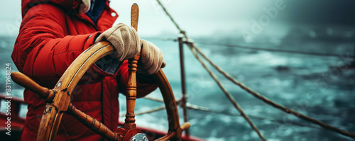 Captain with hands on the ship rudder steering the boat. With copy space and sea background. photo