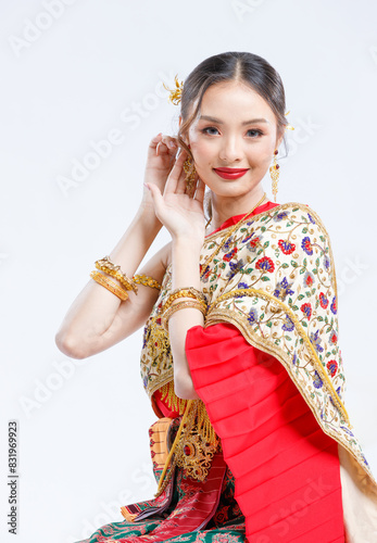 Half body shot, Asian young female portrait beautiful bride woman in vintage traditional Thai costumes, gold and red color dress, sitting smile looking camera isolated white background studio.