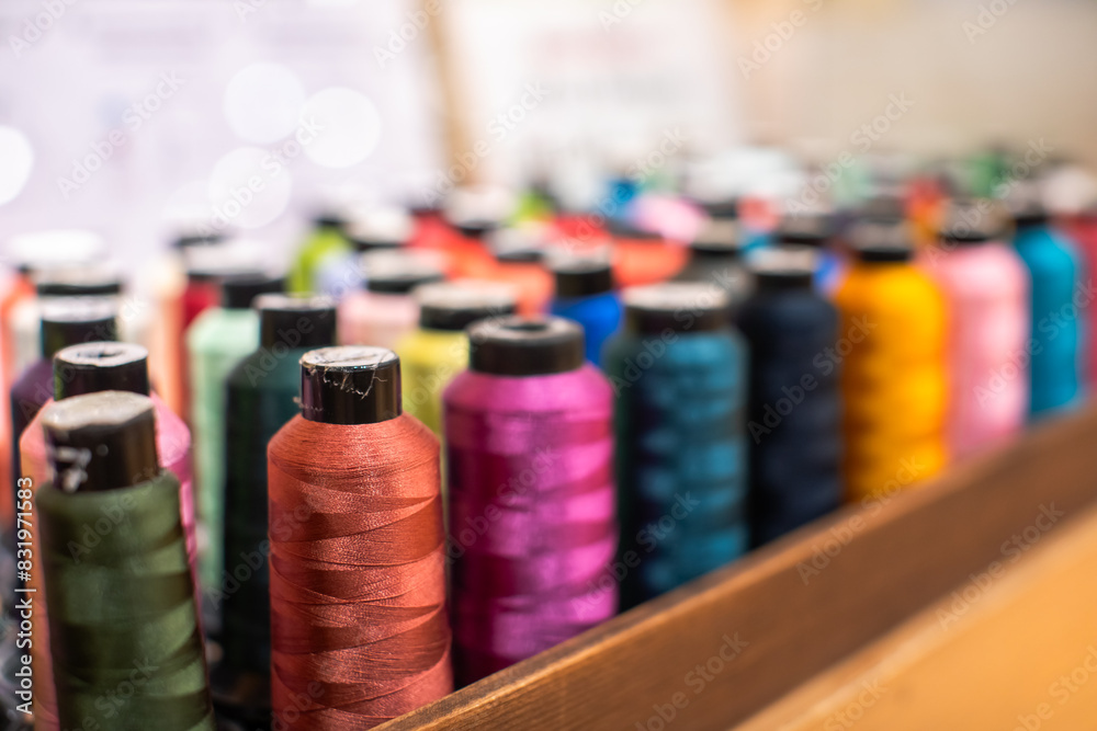 Selective focus to colorful sewing threads in a sewing shop. Repair or correction of clothing sizes. Selective focus to colorful sewing threads in a sewing shop. Repair or correction of clothing sizes.