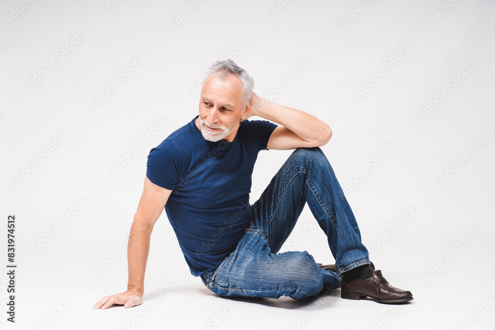 Portrait of adult gray-haired man in casual posing isolated over white background sitting on floor Portrait of adult gray-haired man in casual posing isolated over white background sitting on floor
