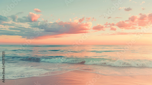 A beautiful beach under a pink and orange sunset sky features a calm sea and a sandy shore.