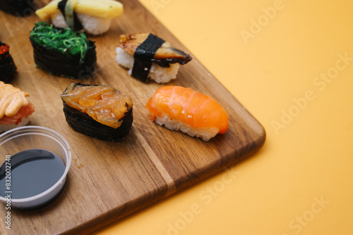 Sushi platter. A selection of raw fish and rice snacks with chopsticks on yellow background. photo