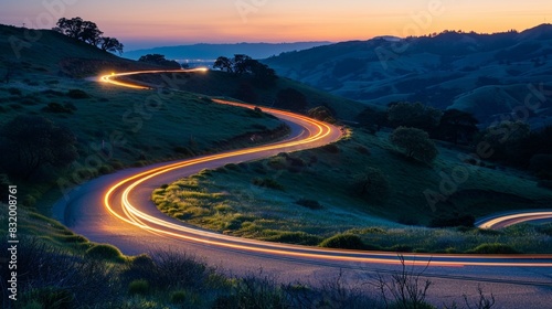 A winding country road at dusk with light trails from car headlights.