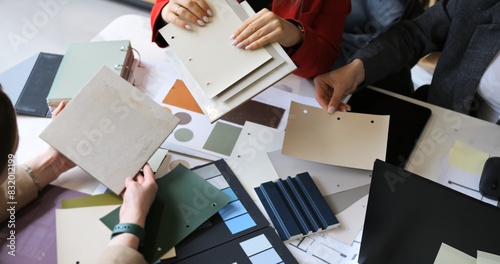 Fashion designers choosing fabric swatches in creative meeting. Professionals discuss textile selections color patterns. Collaborative session focuses on innovative design ideas and material planning.