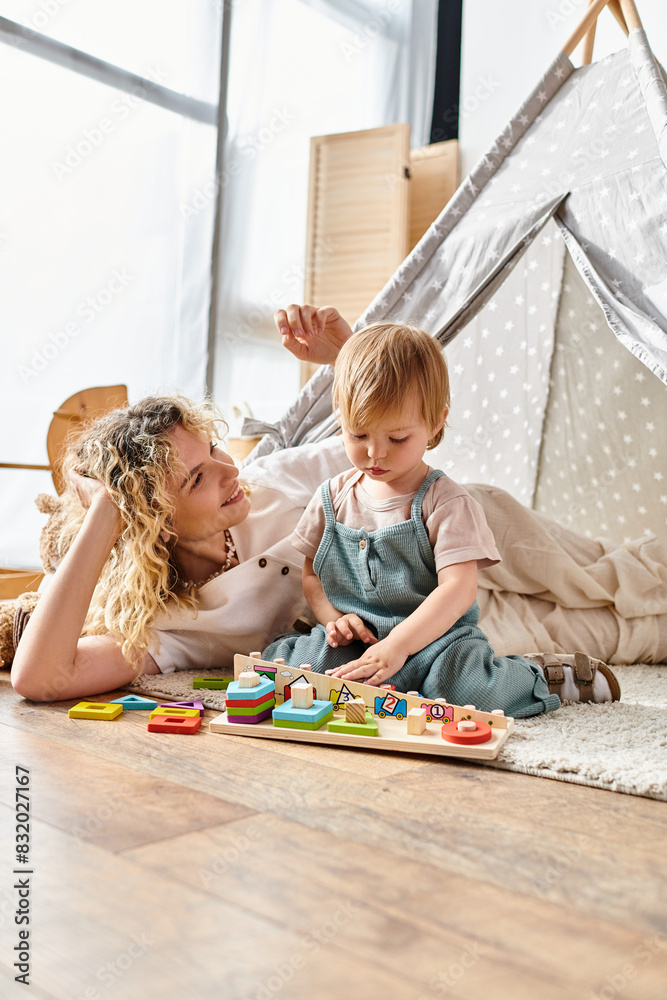Naklejka premium Mother and toddler happily play with Montessori toys on the floor.