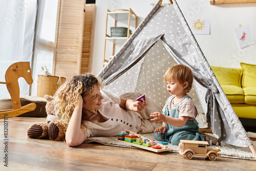Photography Curly mother and toddler daughter happily playing together inside a colorful play tent, embracing the Montessori method of education at home