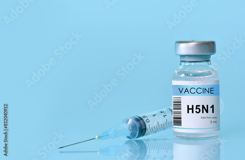Vaccine vial of H5N1 in a bottle with a syringe on a blue background. Bird flu vaccine. The concept of medicine, healthcare and science. Copy space for text. Banner