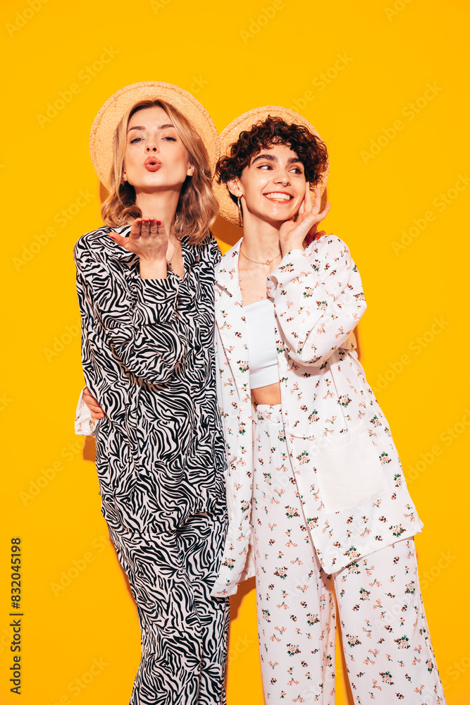 Two young beautiful smiling brunette hipster female in trendy summer costume clothes. Sexy women posing near yellow wall in studio. Positive models having fun. Cheerful and happy Two young beautiful smiling brunette hipster female in trendy summer costume clothes. Sexy women posing near yellow wall in studio. Positive models having fun. Cheerful and happy