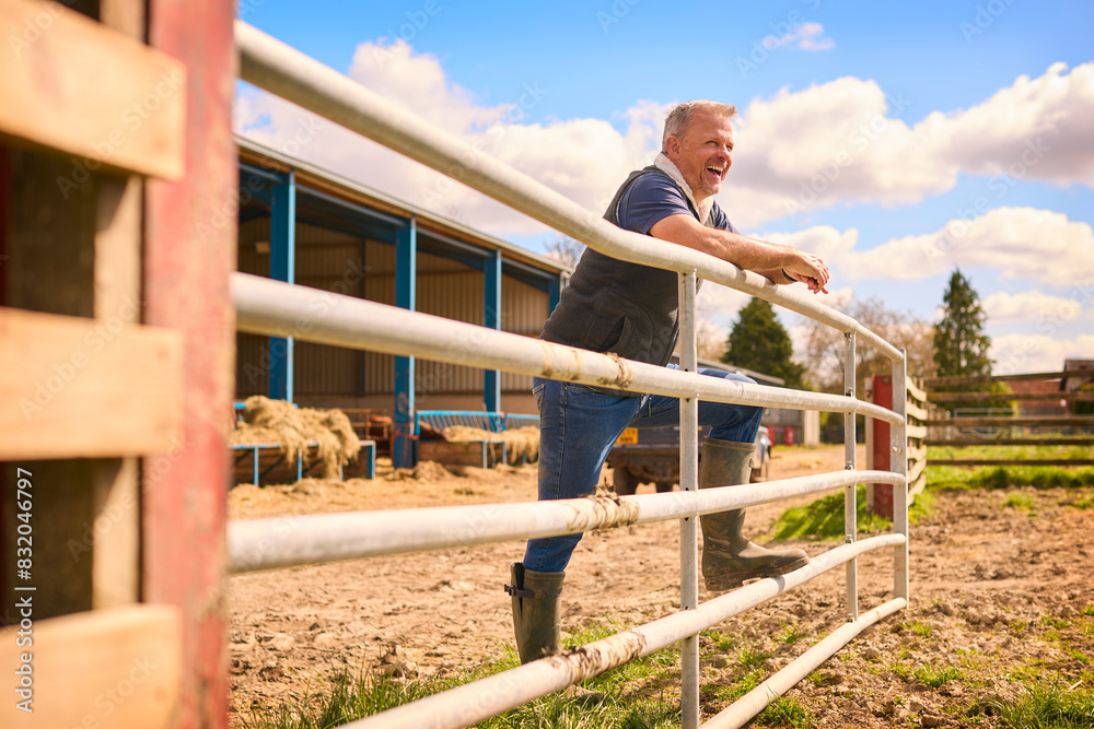 Portrait Of Mature Male Farm Worker Standing By Fence Outside Barn Portrait Of Mature Male Farm Worker Standing By Fence Outside Barn