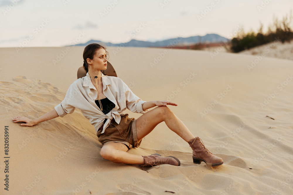 Woman resting on sandy dune with white shirt and brown boots, enjoying peaceful moment in desert landscape