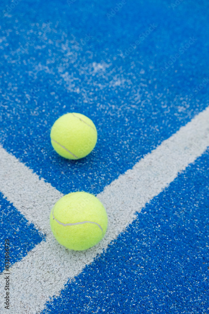 two balls on a blue paddle tennis court, racket sports concept