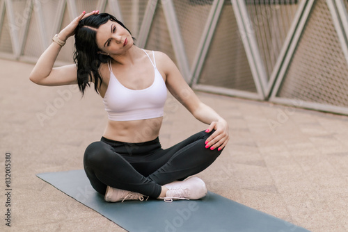 Sportswoman doing streching and yoga exercises outdoors. Shot of a fit young woman stretching  relaxing after a run outdoors in urban town for health. Healthy sports lifestyle. 