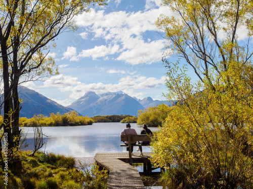 Couple on a bench looking out over Lake Wakatipu, Otago Region, South Island, New Zealand, Pacific photo