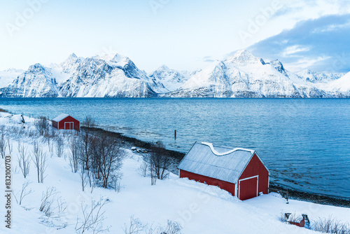 Elevated view of typical red rorbu on the shore of the fjord surrounded by snowy peaks in morning, Djupvik, Olderdalen, Lyngen fjord, Lyngen Alps, Troms og Finnmark, Norway, Scandinavia photo