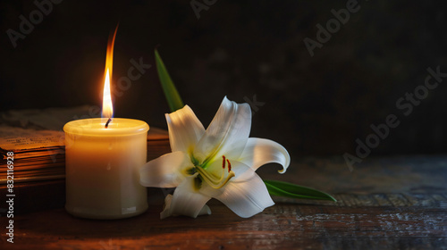 Burning candle book and white lily on table in darknes