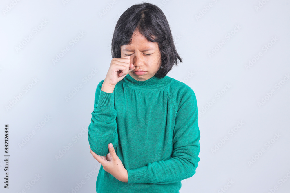 Asian little girl crying and wiping tears with hand over grey background. Asian little girl crying and wiping tears with hand over grey background.