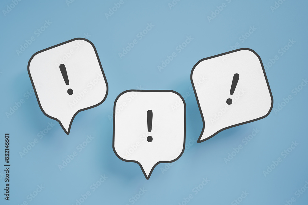 Exclamation mark on real white paper cut speech bubble on blue background Exclamation mark on real white paper cut speech bubble on blue background