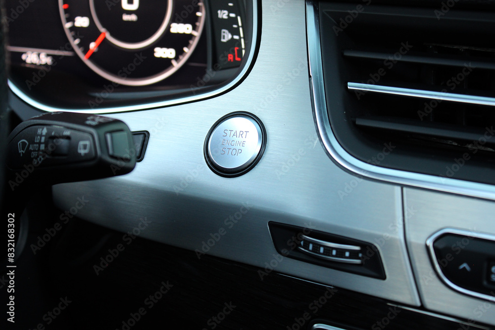 Car start stop system button in car interior. Car Ignition Key. Silver Start stop engine button in lux SUV. Close up engine car start button in dashboard. Car start stop system button in car interior. Car Ignition Key. Silver Start stop engine button in lux SUV. Close up engine car start button in dashboard.