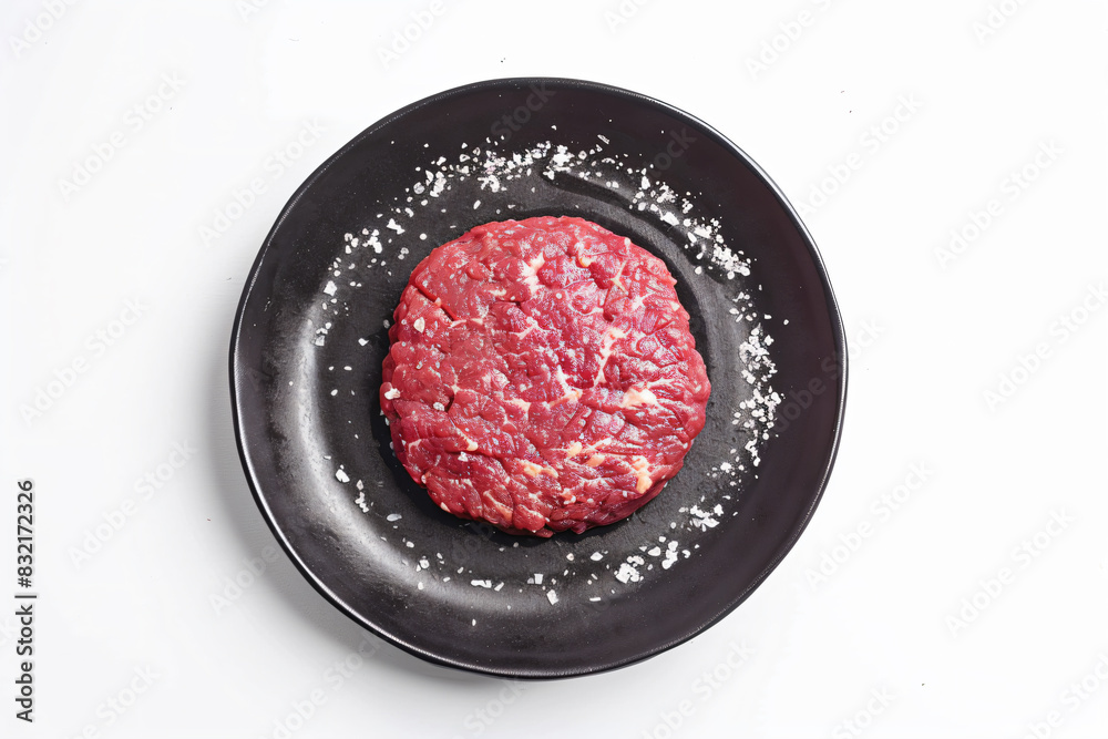 a steak patty on a black plate with salt a steak patty on a black plate with salt