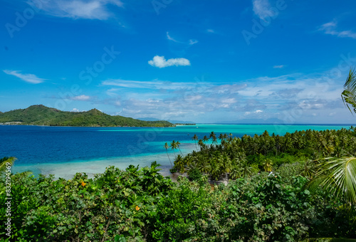 Wallpaper Mural A stunning vista of a tropical beach with lush greenery leading to a clear blue sea and a cloud-flecked sky above. An island looms in the distance, completing the serene landscape. Torontodigital.ca
