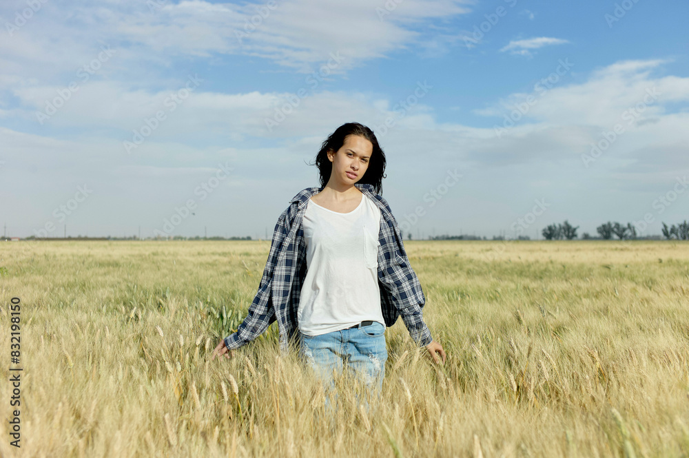 A woman stands in the middle of a golden wheat field with a contemplative expression, her arms relaxed at her sides. A woman stands in the middle of a golden wheat field with a contemplative expression, her arms relaxed at her sides.
