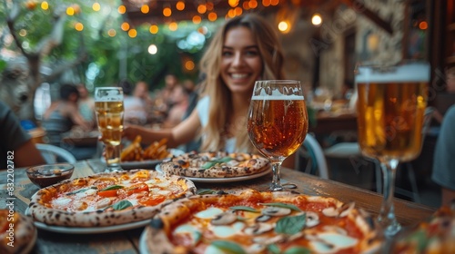An attractive woman enjoys pizza and beer with friends at an outdoor café, with string lights above